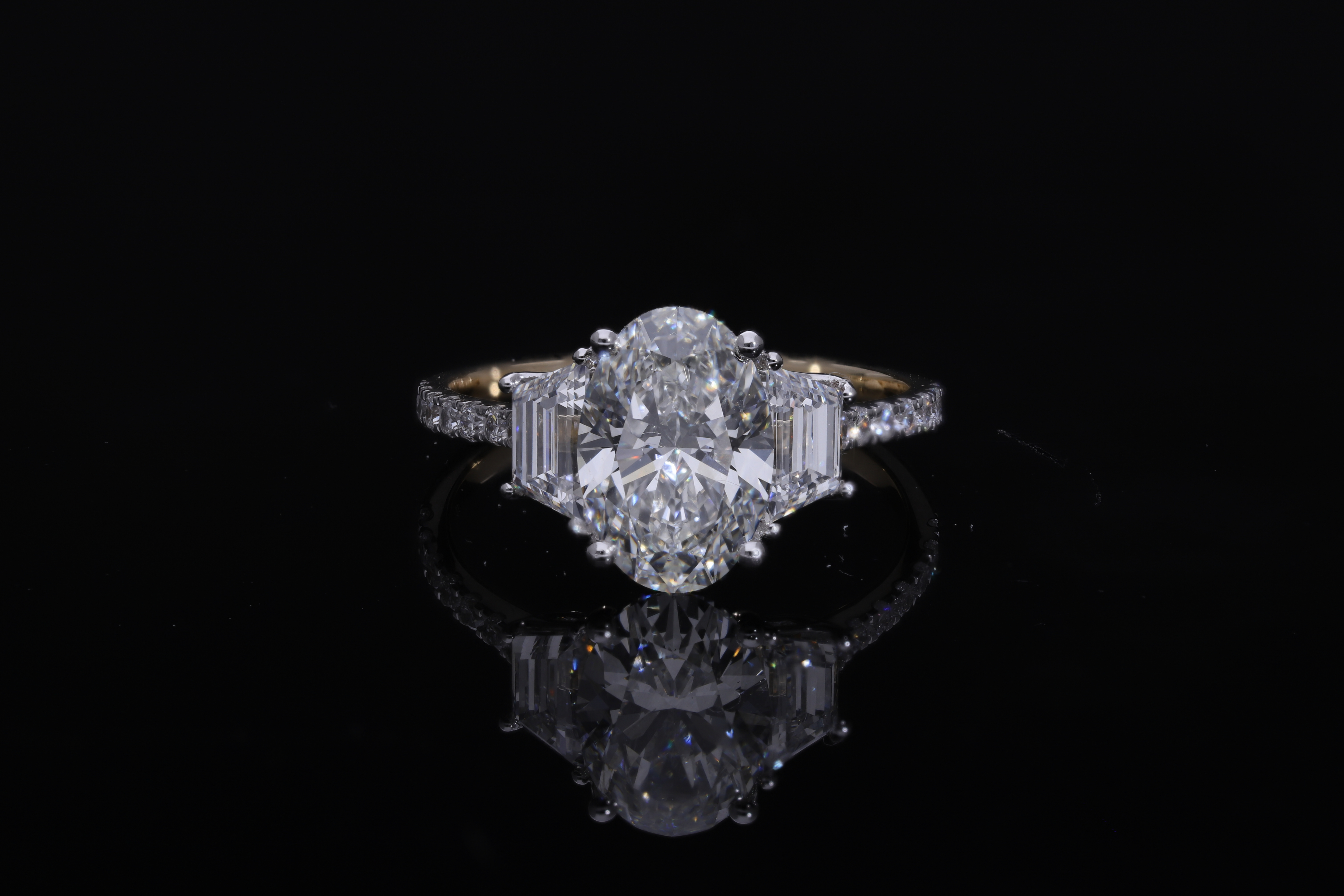 center oval with fancy trapezoid and round brilliant cut diamond engagement ring